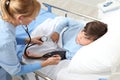 Child lying in bed in hospital room and nurse measuring his pressure with sphygmomanometer and stethoscope Royalty Free Stock Photo